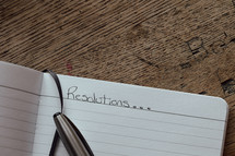 Open notebook with pen and the word "resolutions..."