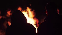 group of young people singing by a campfire 