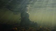 Fly fisherman’s net resting in a river during sunrise