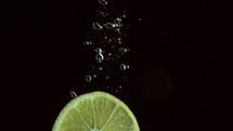 Lemon slice plunging into water 