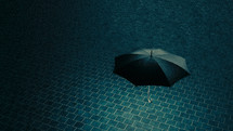 Black umbrella hovering above blue tile