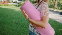 Young woman walking to do yoga with pink mat
