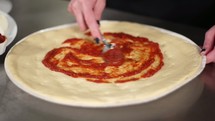 putting sauce on a pizza 