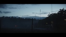 A football field behind a fence on a misty evening