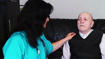 Senior man talking with nurse caregiver at home