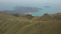 Aerial drone shot of small houses on a hill on Lantau Island in Hong Kong with an ocean in the background.