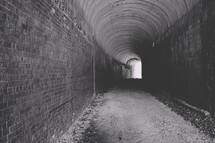 Arched brick tunnel with light at the end
