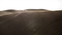 Sunlight in desert. Wind blowing sand and dust over middle eastern desert sand dunes in United Arab Emirates landscape during evening sunset in cinematic slow motion.