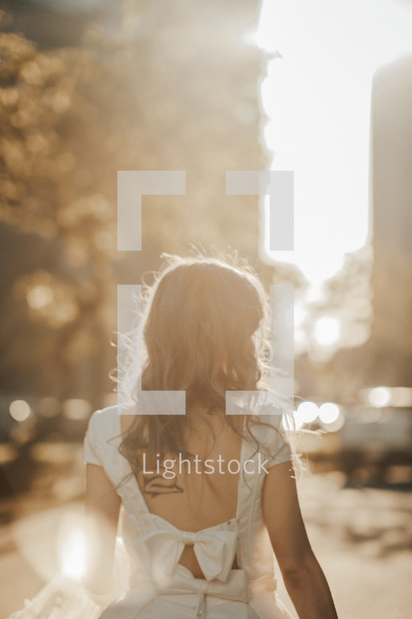 a bride walking in bright sunlight in a city 
