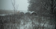 Snowflakes, snow flakes falling in slow motion during winter snow storm on hay bales on farmland.