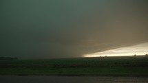 Dark, scary, severe thunderstorm moves over rural farmland in Kansas. Lightning and rain in dark storm clouds in distance over farmland.