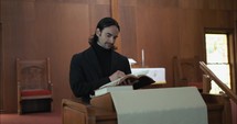 Young pastor in church with bible preaching, teaching sermon to congregation in Sunday morning worship service.