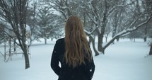 Woman model in winter coat standing outside on Christmas watching slow motion snow as snowflakes fall in cinematic slow motion.