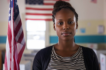AI Image. Confident young African American woman in a voting room with USA flag