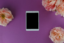 iPad and pink peonies on a purple background 