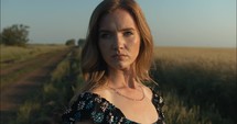 Portrait of young woman with serious expression looking at camera during golden hour outdoors.