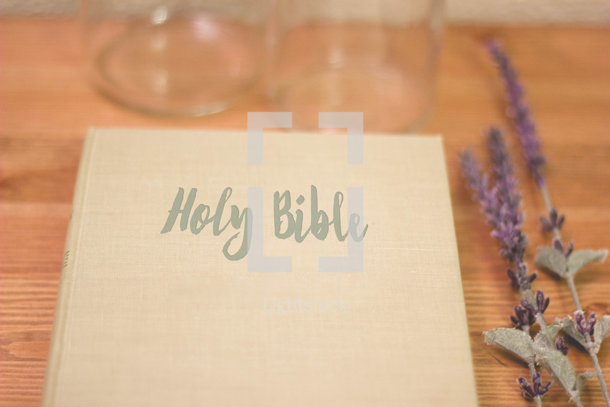Holy Bible, lavender, and glass bottles on wood 