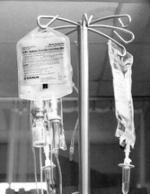IV Patient Care Hospital  - A black and white image of an IV drip hanging over a patient in a hospital bed. 