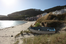 small dinghy resting on the dunes of a beach