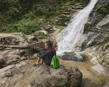 Girl Sitting On Rock By Waterfall