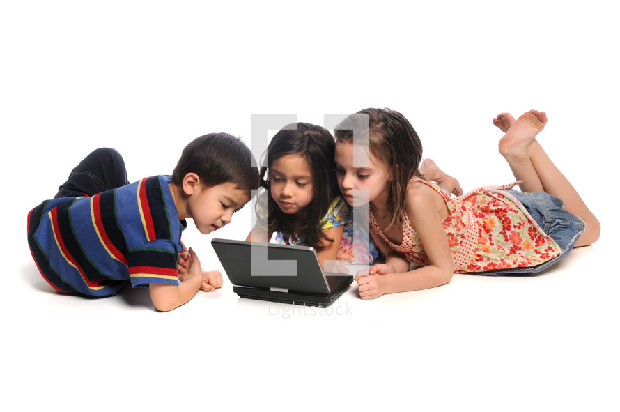 Three children on the floor looking at a laptop computer.