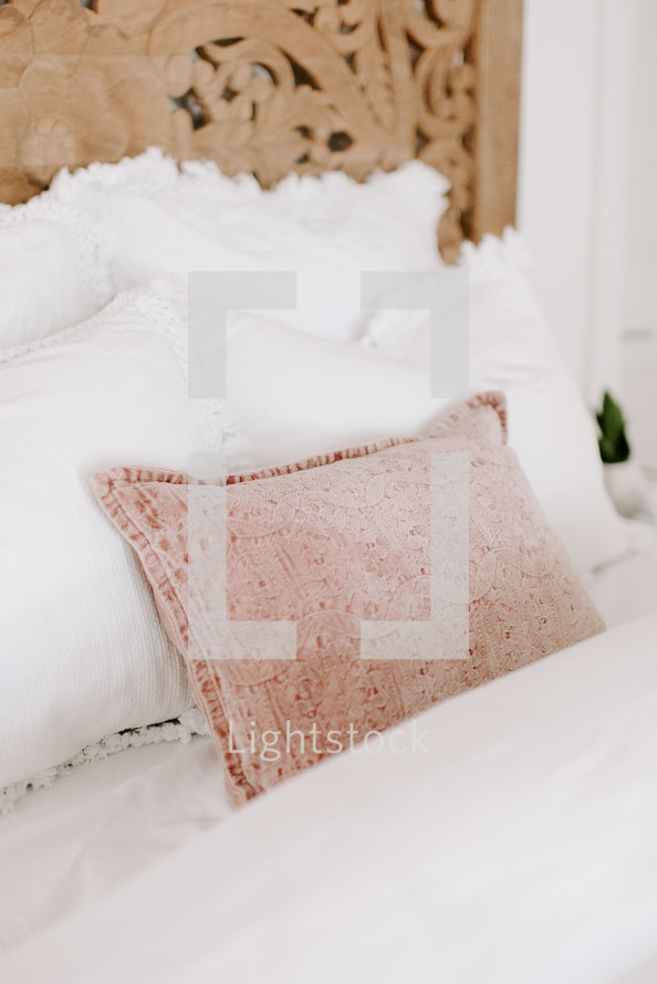 blush pillow on a bed 