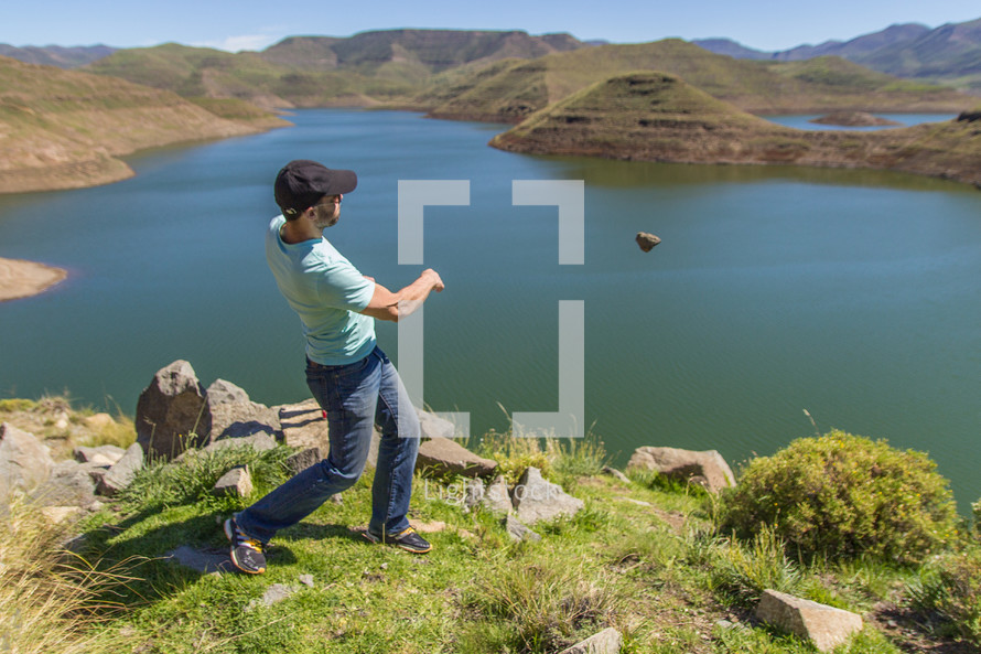 a man throwing a rock into a lake 