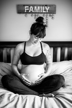 pregnant mother sitting on a bed 