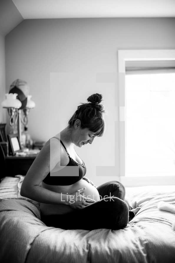 pregnant mother sitting on a bed 