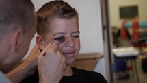 Makeup is applied to a young man actor for theater play.