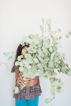 teen girl holding eucalyptus in front of her face 
