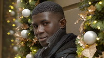 young man with blank stare surrounded by Christmas decorations 