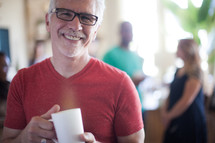 A smiling man holding a cup of coffee.