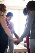 A small group of women holding hands and praying.
