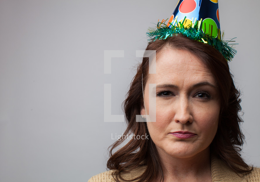 woman in a party hat with a frown 