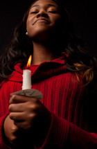 A woman holding a candle at a Christmas Eve service. 