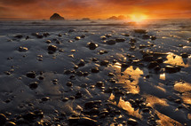 pebbles on wet sand and vibrant orange sky at sunrise 