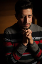 a latino man with praying hands 