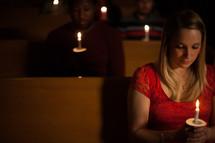 parishioners sitting holding candles at a Christmas Eve worship service 