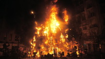 A burning installation with doll figures during the Las Fallas feast in Valencia, camera unzooms to the wide shot