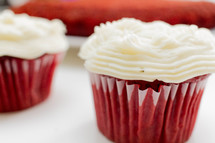 Cupcakes with white icing in red paper cups.