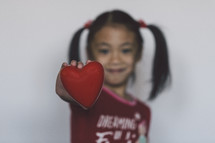 a child holding out a red heart 