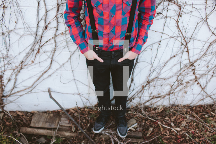a teen boy in suspenders and a flannel shirt 