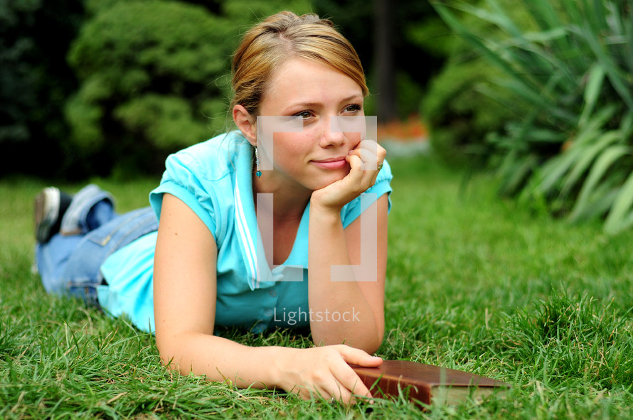 teen girl reading a Bible outdoors 