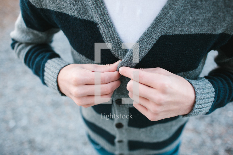 a man fastening a button on his sweater 