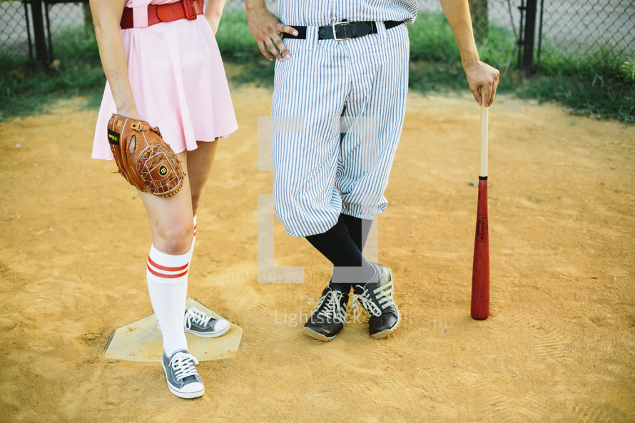 a couple in baseball uniforms standing on a baseball field 