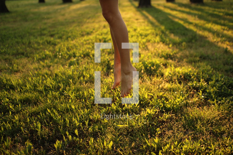 feet of a little girl lifting up off of grass