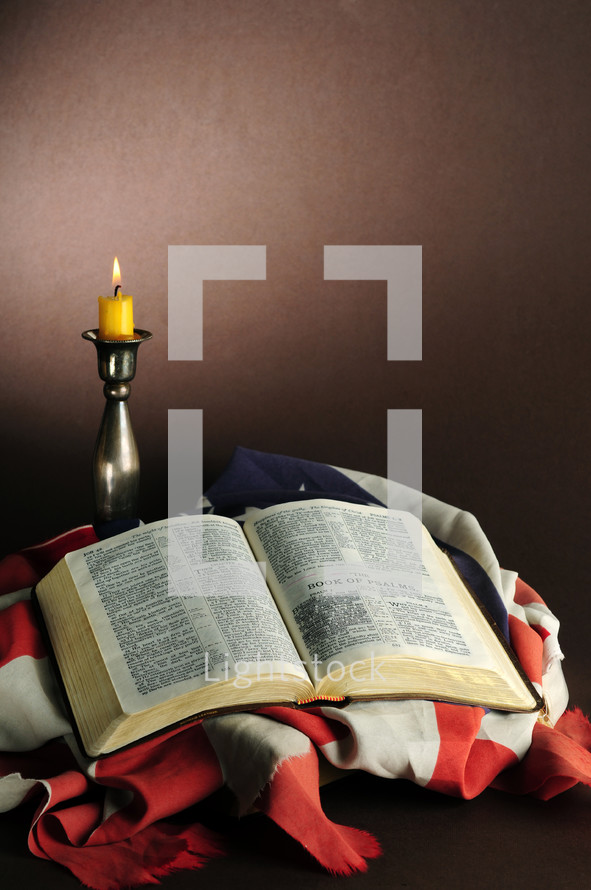 candlestick and open Bible on an American flag 