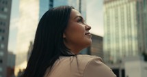 Young woman admiring downtown city buildings and scenery during sunset