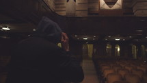 hooded man leaving an empty church 